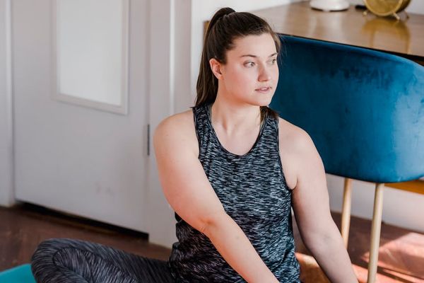 Woman performing a focused yoga stretch in a calm, minimalist room.